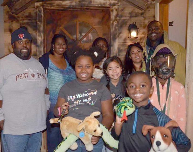 Nine family members of all ages posed together on a family outing, several of the children holding stuffed animals.